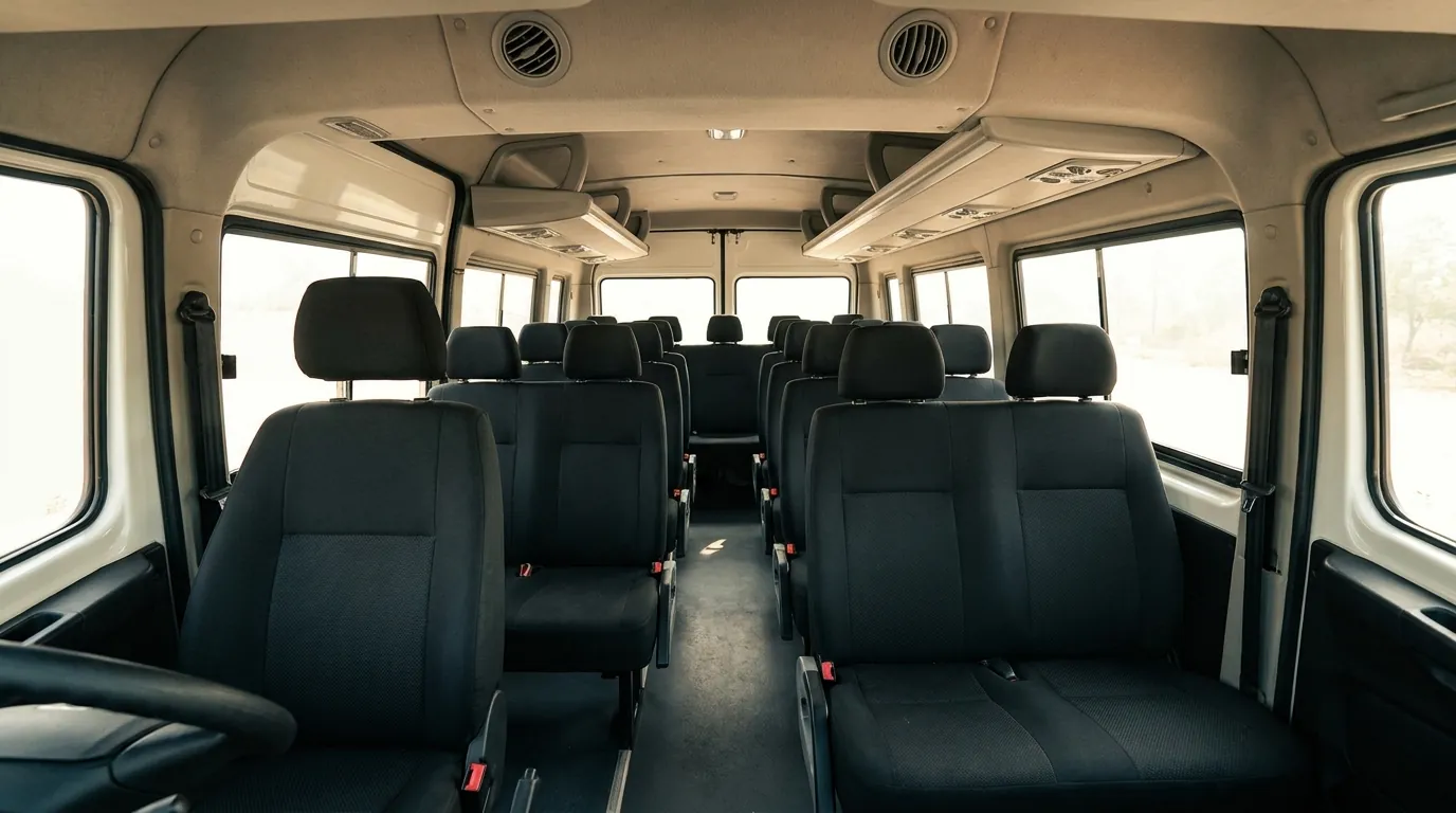 Inside a 17-seater Tempo Traveller: push-back seat rows running back to the rear of a long cabin